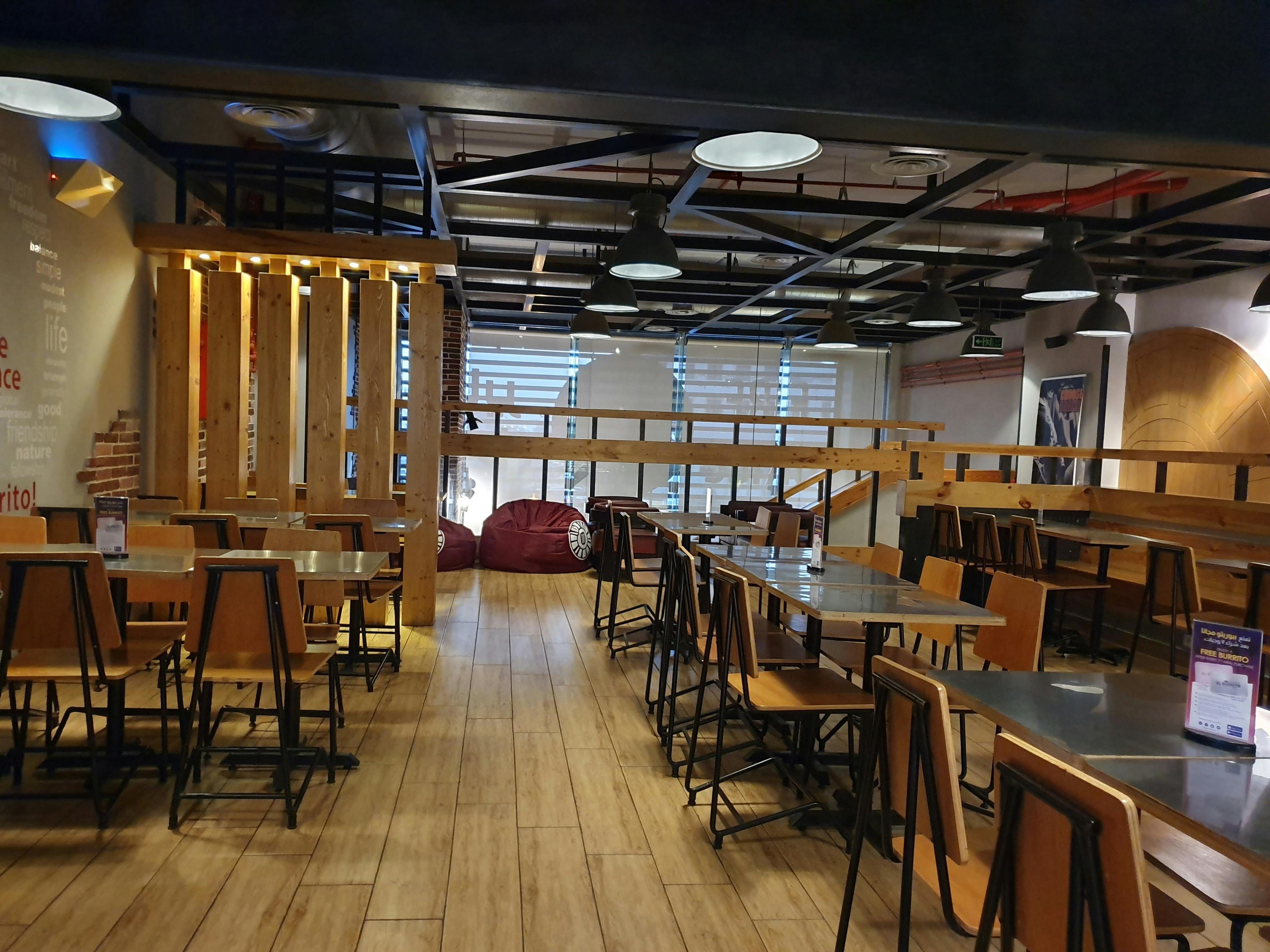 Modern restaurant interior with wooden tables, warm lighting, and welcoming atmosphere